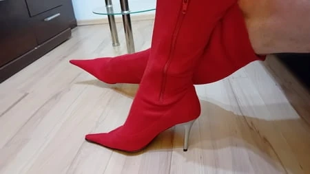Seksi kırmızı süetli travesti ayak parmaklarına yüksek topuklu çizmeler gösteriyor